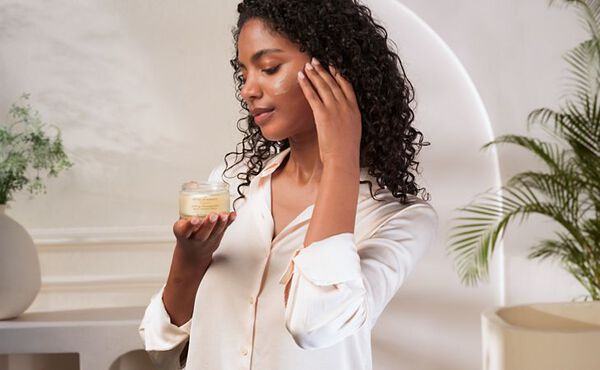 A woman applies Rituls melting cleansing balm to her face, enjoying a moment of self-care in a calming bathroom.