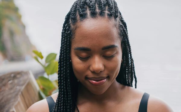 Vrouw met gevlochten haar mediteert vredig met gesloten ogen en belichaamt de Ayurvedische principes van innerlijke balans.