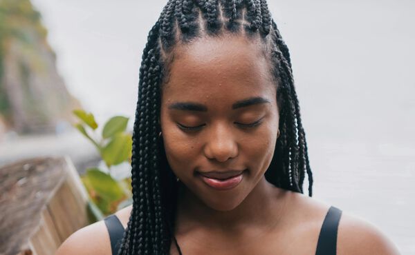 Woman with braided hair meditating peacefully with closed eyes, embodying the Ayurvedic principles of inner balance.