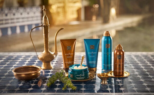 The Ritual of Hammam products displayed on blue tiles with a brass teapot and bowl for a home spa atmosphere.