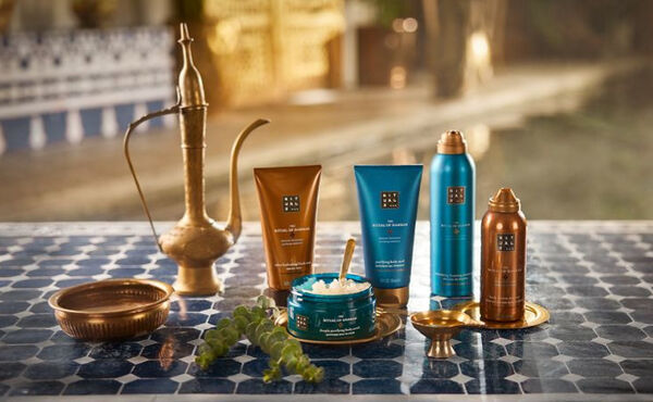 Productos The Ritual of Hammam colocados en el estante de un baño, con accesorios de cobre para crear una elegante experiencia de spa en casa.