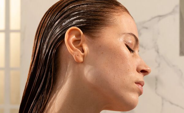 Une femme de profil, les cheveux mouillés plaqués en arrière. Ses yeux sont fermés.