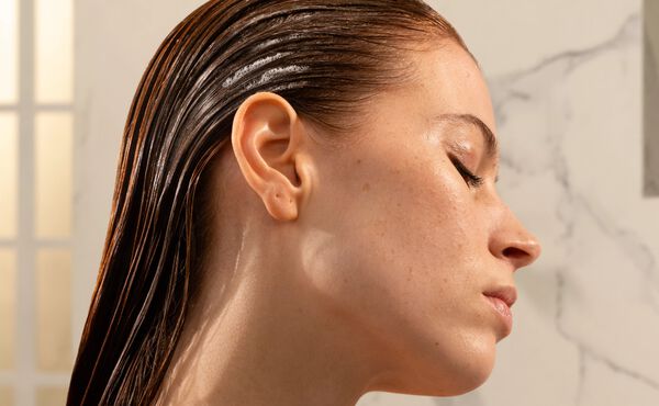En sideprofil av en kvinne med vått, glatt, bakoverstrøket hår. Øynene hennes er lukket.