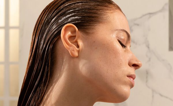 El perfil de una mujer con el pelo negro mojado y peinado hacia atrás. Tiene los ojos cerrados.