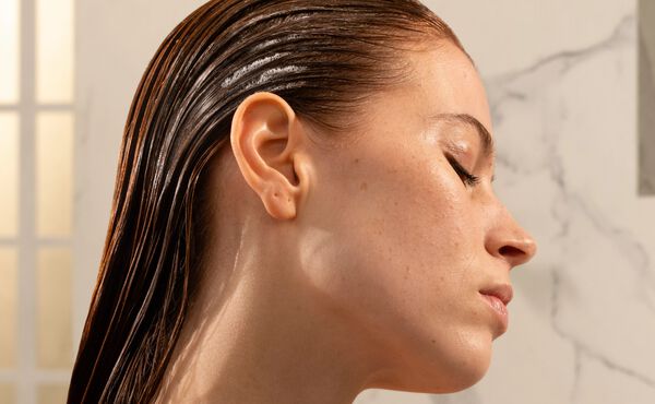 A side profile of a woman with wet slicked-back hair. Her eyes are closed.