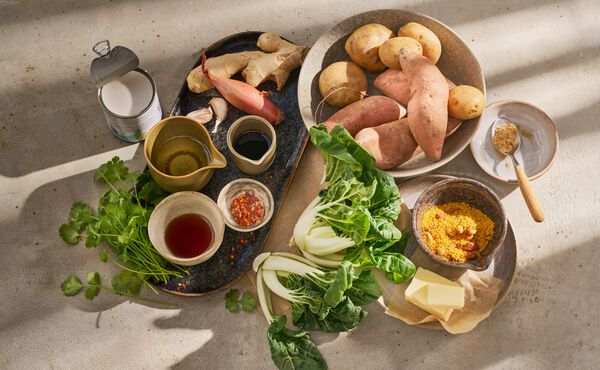 Ingredientes frescos para preparar una receta buena para el estómago, que incluyen batata, pak choi, miso, leche de coco y jengibre.