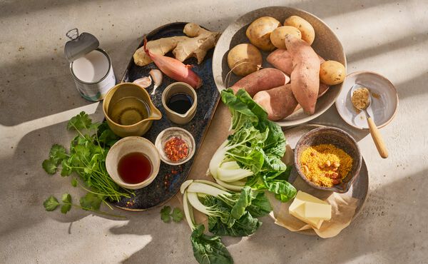 Ingredienti freschi per una ricetta amica dell’intestino, tra cui patate dolci, pak choi, miso, latte di cocco e zenzero.