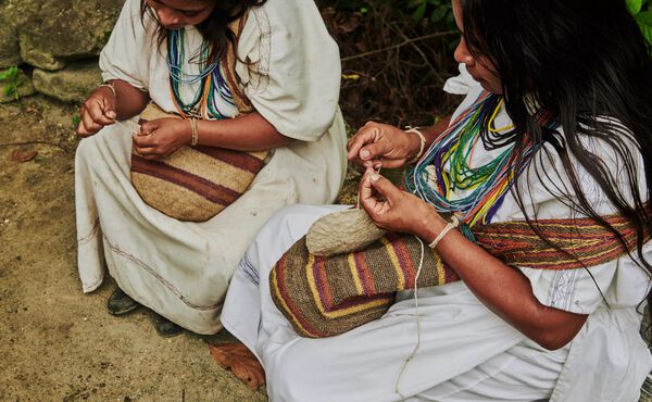 Arhuaco women hand-weaving traditional bags in Colombia. Ancestral craft rooted in spiritual connection to nature.