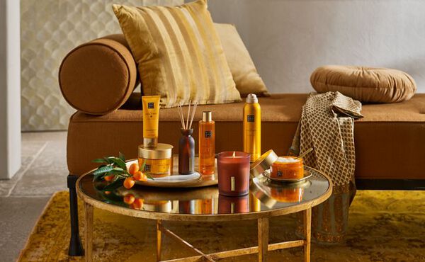 The Ritual of Mehr products styled on a golden table, reflecting uplifting energy with vibrant yellow and orange packaging.