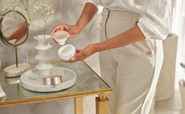 En Ritual of Namaste refill settes i en gjenbrukbar hudpleie-krukke som del av en bærekraftig hudpleierutine.