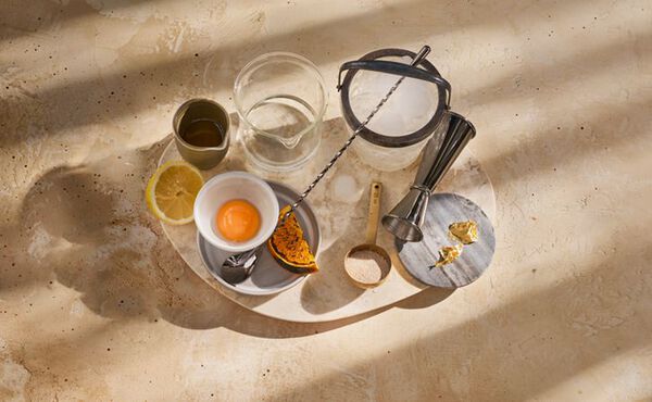 Gin sour mocktail ingredients including egg yolk, lemon, pumpkin and spices, arranged on a tray ready for mixing.