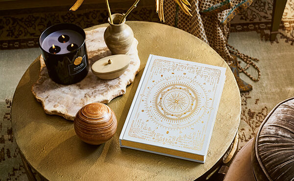 El libro decorativo The Book of Rituals sobre una mesa con una vela aromática grande Rituals Private Collection.