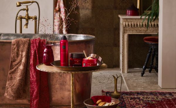 The Ritual of Ayurveda products styled in a luxurious copper bathroom, with red packaging reflecting balance and warmth.
