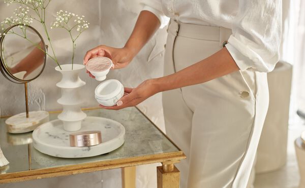 Inserting a Ritual of Namaste refill pod into a reusable face cream jar as part of a sustainable skincare routine.