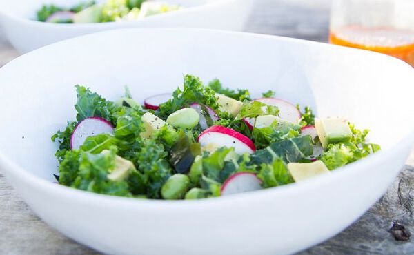 Fresh kale and radish salad with avocado and edamame, served as a healthy vegan dinner idea.