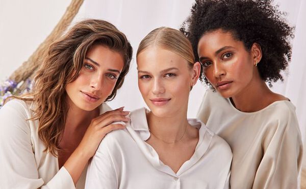 Three women with glowing skin pose together, representing confidence and skincare for all skin types.