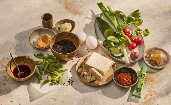 Ingredients for a healthy black rice bowl recipe, including vegetables, tofu, edamame, eggs and sauces.