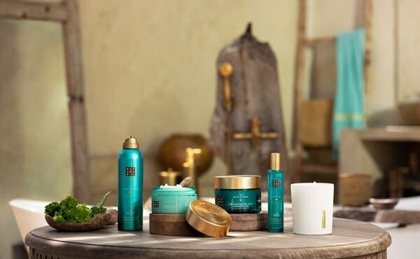 The Ritual of Karma collection displayed in a summer holiday setting, with uplifting turquoise packaging.