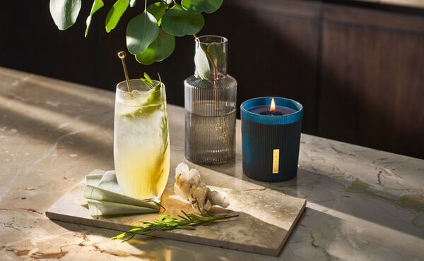 The Ritual of Hammam mocktail with fresh herbs and citrus, paired with a matching scented candle and elegant glassware.