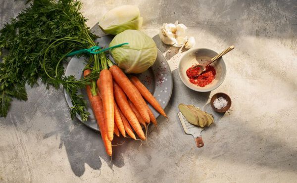 Fresh carrots, cabbage, garlic and spices laid out for homemade kimchi recipe preparation.