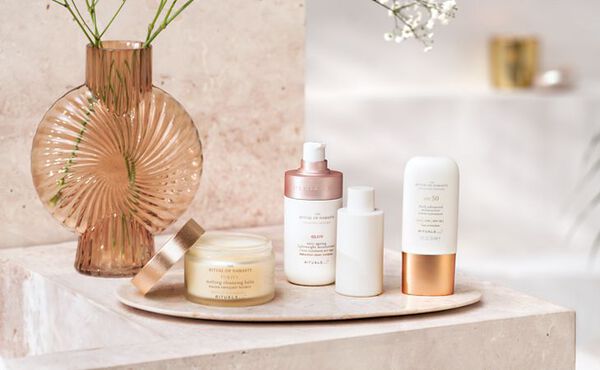 A Rituals skincare set displayed on a stone tray with elegant packaging, featuring cleansing balm and SPF face cream.