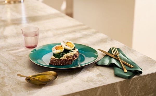 Wholegrain toast with hummus, spinach and boiled eggs on a green plate, a healthy high-protein vegetarian meal.