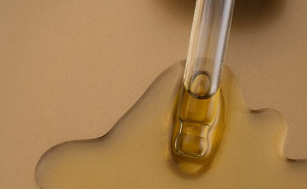 A close-up of a dropper releasing golden facial oil, highlighting the texture and richness of Rituals skincare formulas.