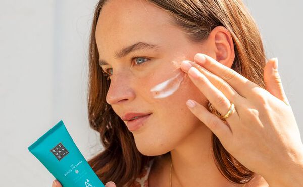 En kvinne påfører The Ritual of Karma after sun serum i ansiktet, noe som beroliger huden og gir bedre fuktighet etter soling.