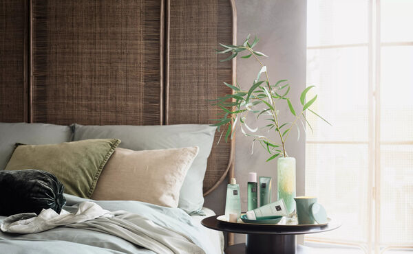 A calming bedroom scene with The Ritual of Jing products arranged on a bedside table to inspire daily wellbeing routines.