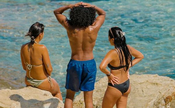 Trois amis en maillot de bain en train de se détendre en bord de mer, profitant du soleil, de leur amitié et de moments d’insouciance estivale.