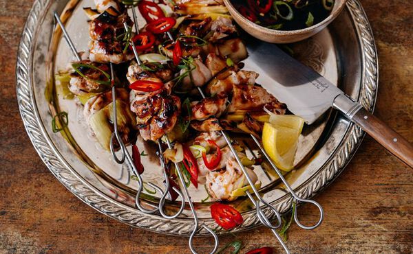 Grilled chicken skewers with red chili, lemon wedges and dipping sauce for a nutritious dinner.