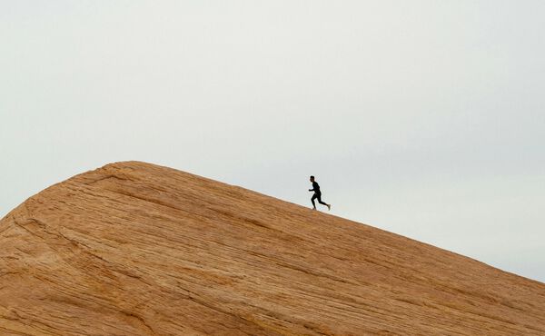 Person running uphill on a rocky slope. A metaphor for building resilience, purpose and a success mindset.