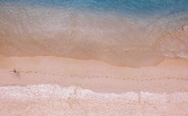 Aerial view of footprints along a tranquil beach, symbolising mindful steps toward your dream life.