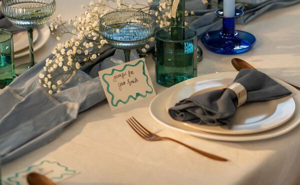 A warm, elegant tablescape featuring festive food, candles, and sparkling drinks on a marble table set for a cosy gathering.
