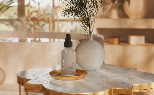 A bottle of Rituals Sport collection magnesium spray for sore muscles, shown on a luxurious marble bathoom counter top.