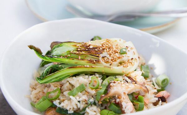 Bowl of healthy stir-fried rice topped with grilled pak choi, spring onions and sesame seeds.