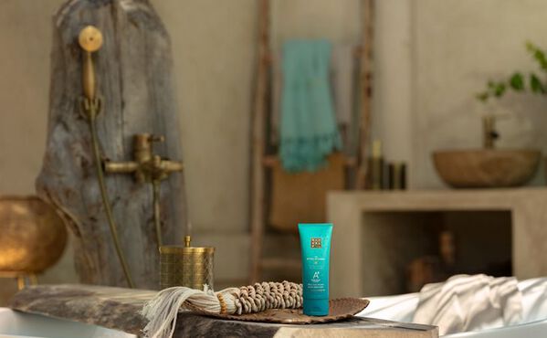The Ritual of Karma after-sun serum plassert ved et badekar i et beroligende spa-inspirert baderom.