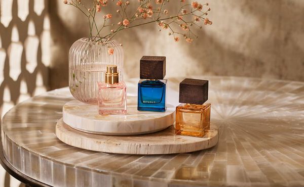 Drei Eaux de Parfum von Rituals, die auf einem dekorativen Tisch als elegante Geschenkideen für Duftliebhaber präsentiert werden.
