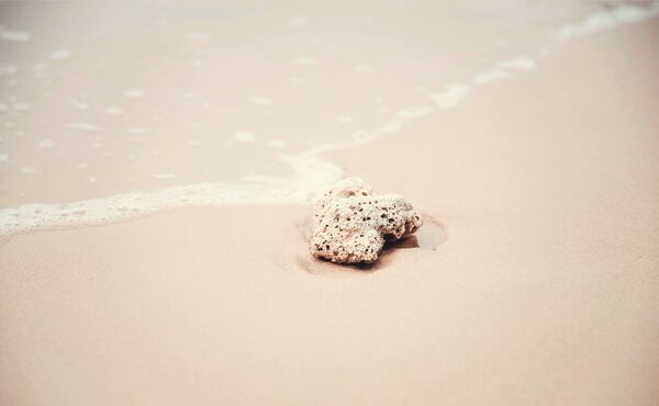Una piedra de coral en la costa con olas que se mecen suavemente, un símbolo tranquilo de causa, efecto y el transcurrir del karma.