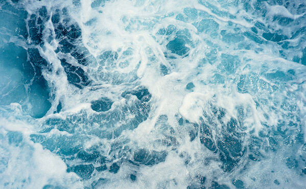 Close-up of swirling blue ocean waves and white foam, capturing water’s movement and energy.