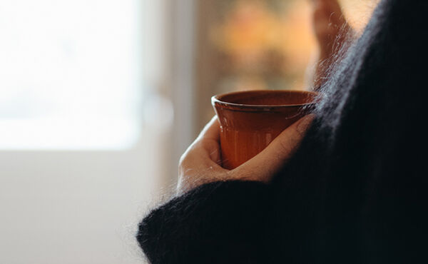 Person holding a warm cup of cacao, enjoying a quiet moment of connection and intention during a cacao ceremony.