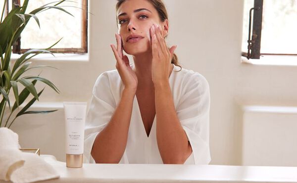 Woman applying The Ritual of Namaste cleanser to her face during a skincare routine.